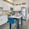a kitchen with white cabinets a kitchen island with chair and stainless steel appliances